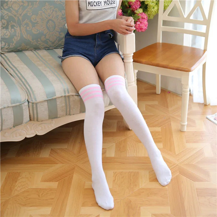 Person wearing white thigh-high socks with pink stripes sitting on vintage sofa in bright room