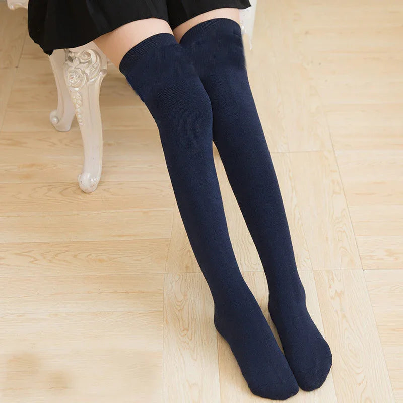 Woman wearing navy blue over-the-knee socks sitting on ornate white chair on light wood floor