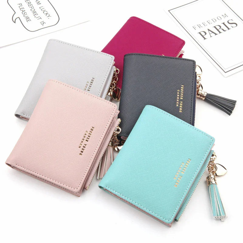 Five compact women's wallets in pink, gray, black, red, and blue with tassel zipper and gold lettering