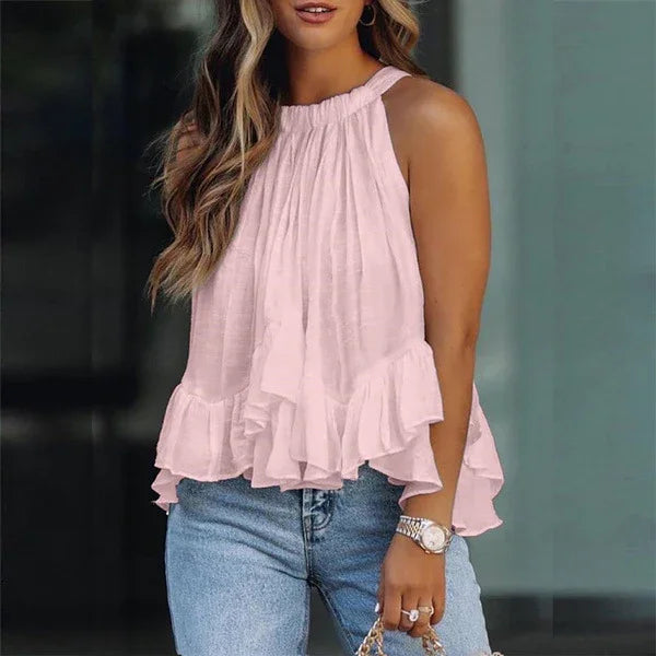 Woman wearing a sleeveless light pink ruffled blouse paired with blue jeans and a wristwatch
