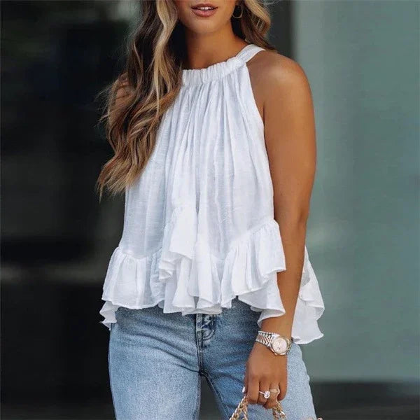 Woman wearing a white sleeveless ruffled blouse paired with light blue jeans and a silver wristwatch