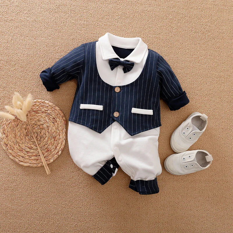 Navy blue and white baby boy formal romper with bow tie and white shoes on beige carpet