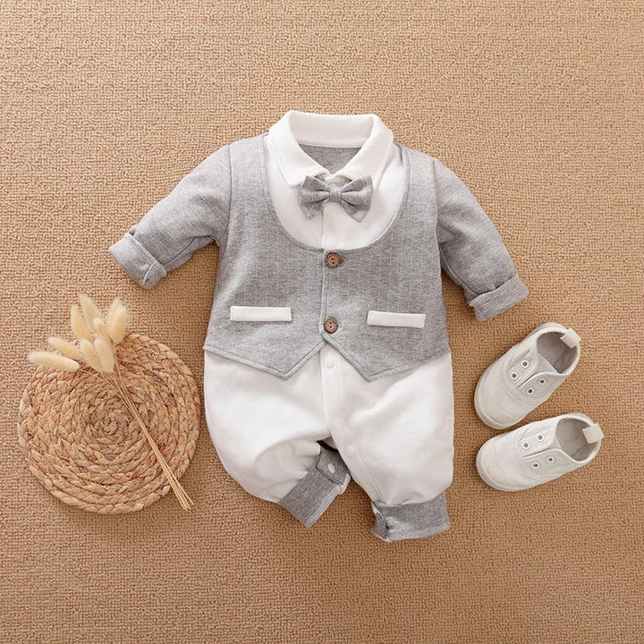 Baby boy formal romper with grey vest and bow tie, paired with white shoes on beige background