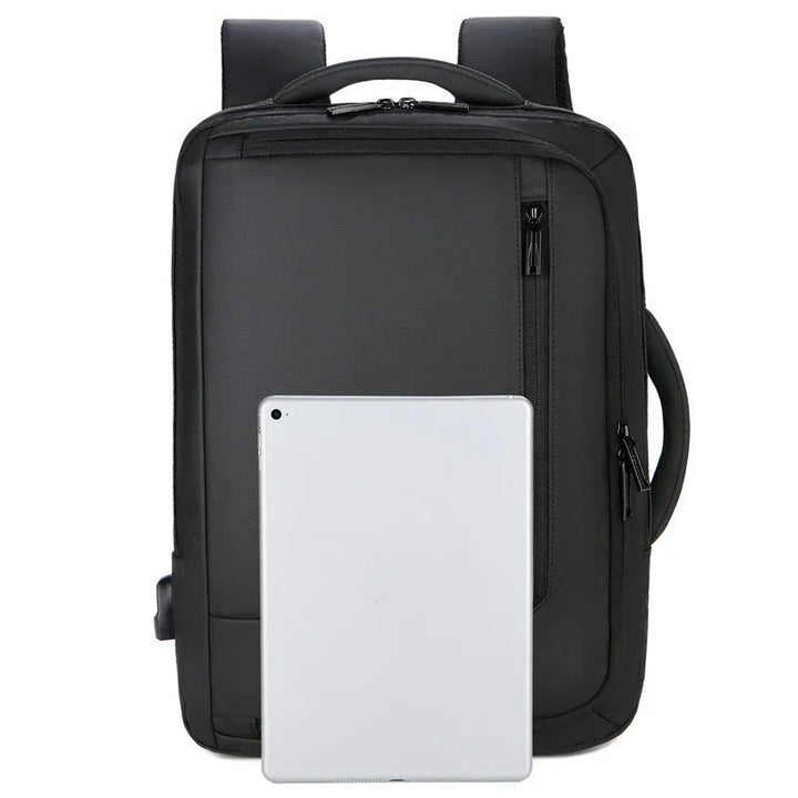Black rectangular backpack with multiple zippered compartments and padded shoulder straps, tablet placed in front