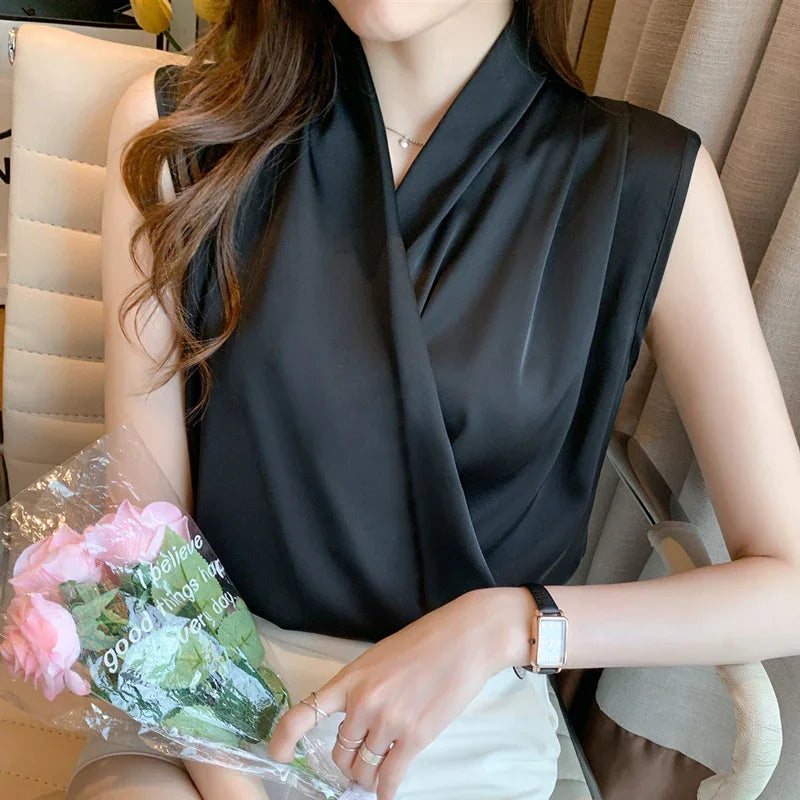 Woman wearing sleeveless black satin blouse holding bouquet of pink roses indoors