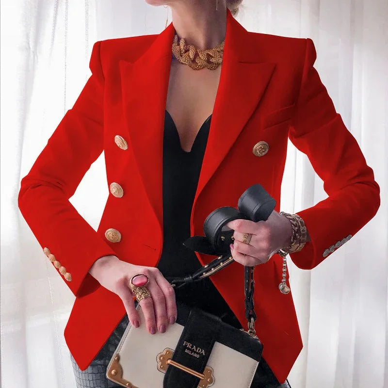 Woman wearing red blazer with gold buttons, chunky gold necklace, holding black and white Prada handbag