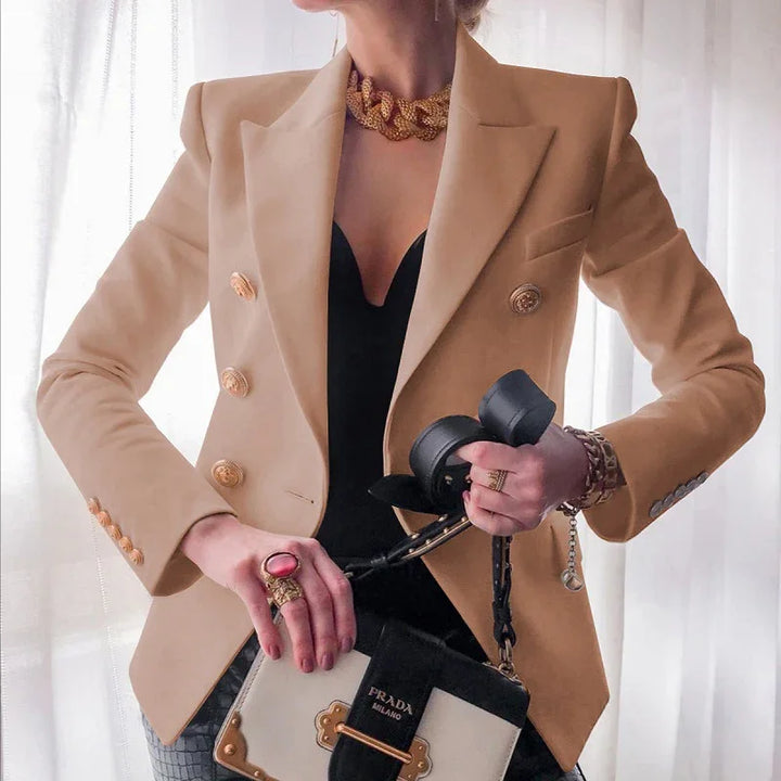 Woman wearing beige double-breasted blazer over black top, holding black and white Prada Milano handbag