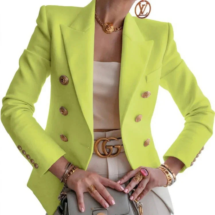 Woman wearing neon yellow blazer with gold buttons, beige top, Gucci belt, gold jewelry, and holding a gray handbag