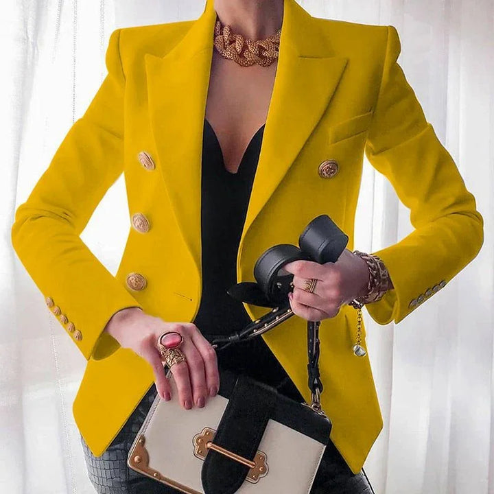 Woman wearing yellow blazer and black top holding black and white designer handbag with jewelry