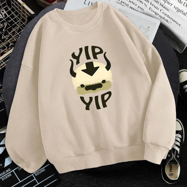 Beige sweatshirt with cartoon Appa face from Avatar and text 'Yip Yip' in casual flat lay