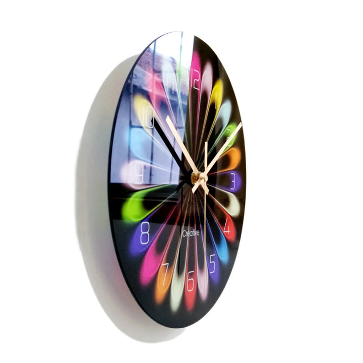 Round black wall clock with colorful petal-shaped hour markers and white hands on white background