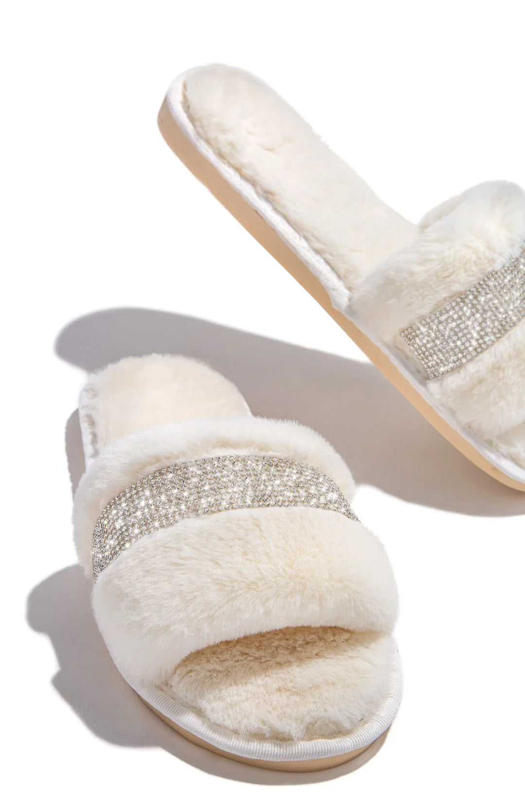 Soft cream faux fur slippers with rhinestone embellishments on white background