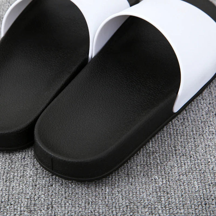 Close-up of black and white slide sandals on gray textured carpet