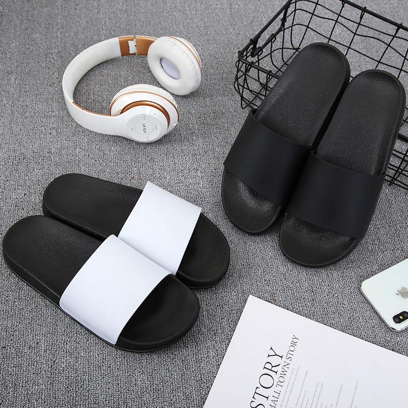 Pair of black and white slide sandals on gray carpet with white headphones and an iPhone nearby