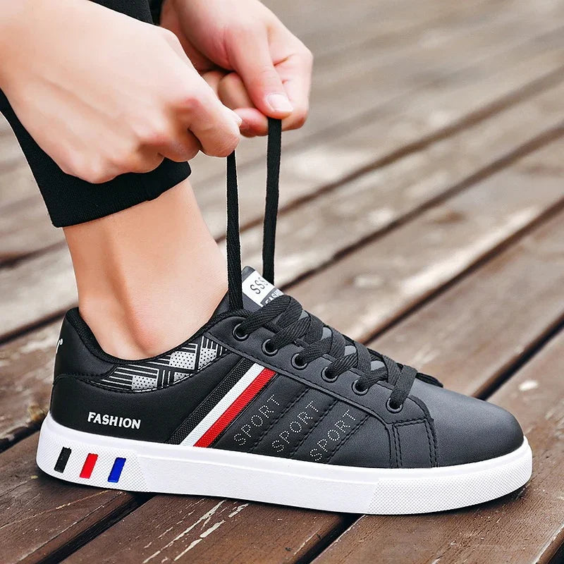 Close-up of black fashion sport sneakers with red and white stripes tied by hands on wooden floor