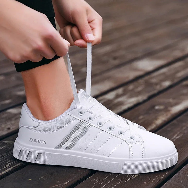 Close-up of hands tying white casual fashion sneakers on wooden floor