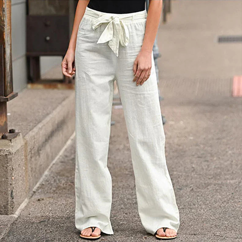 Woman wearing white wide-leg linen pants with a tied waistbelt on urban street