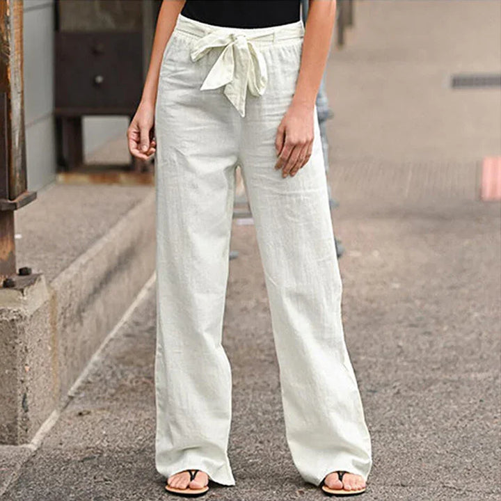 Woman wearing white wide-leg linen pants with a tied waistbelt on urban street