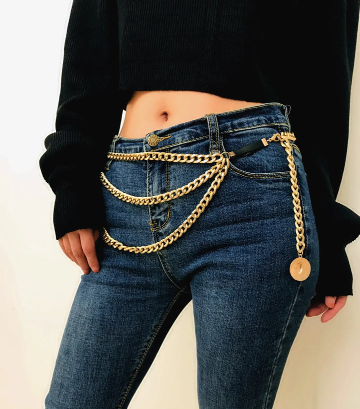 woman wearing dark blue jeans with layered gold chain belt and black cropped sweater