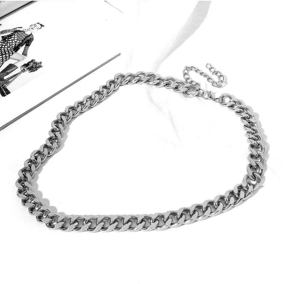 silver chunky chain necklace on white surface next to fashion magazine page