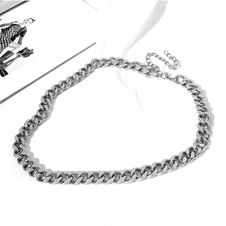 silver chunky chain necklace on white surface next to fashion magazine page