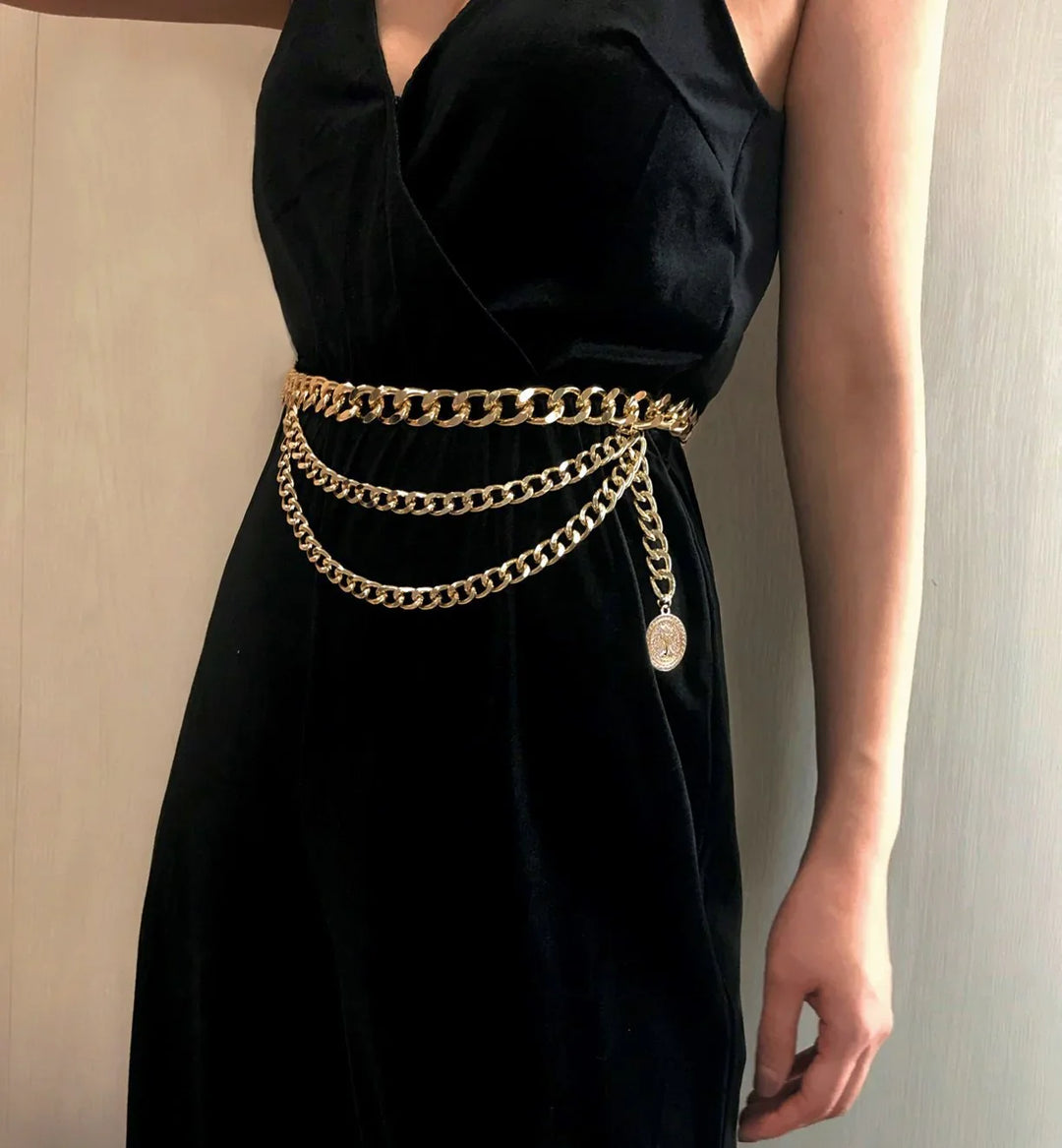 Woman wearing black velvet dress with layered gold chain belt featuring a coin pendant