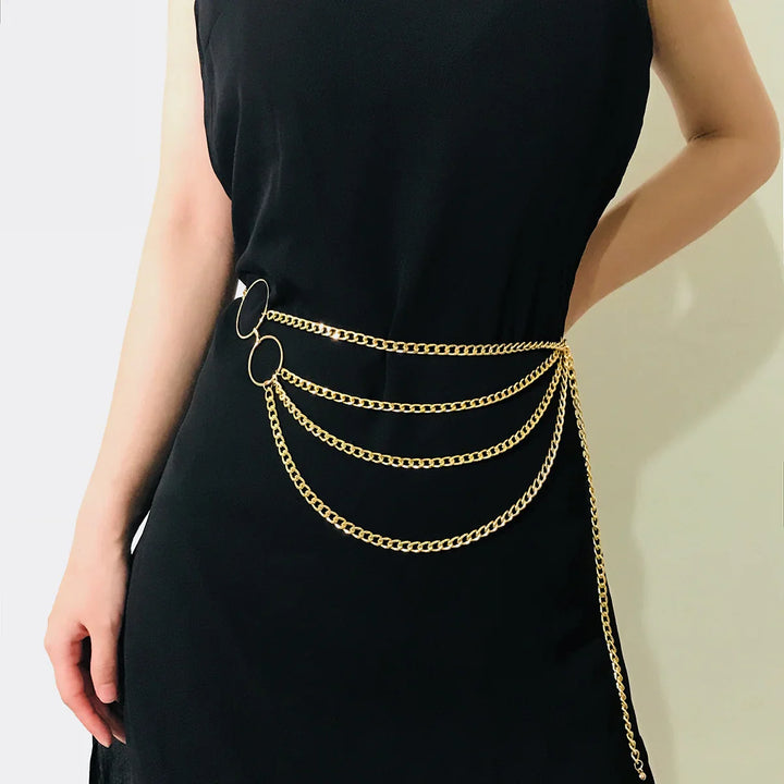 Waist chain belt with gold chains and rings worn over a black sleeveless dress