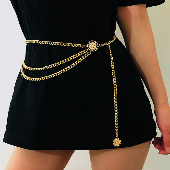 Gold chain belt with decorative medallions worn over black dress, stylish waist accessory