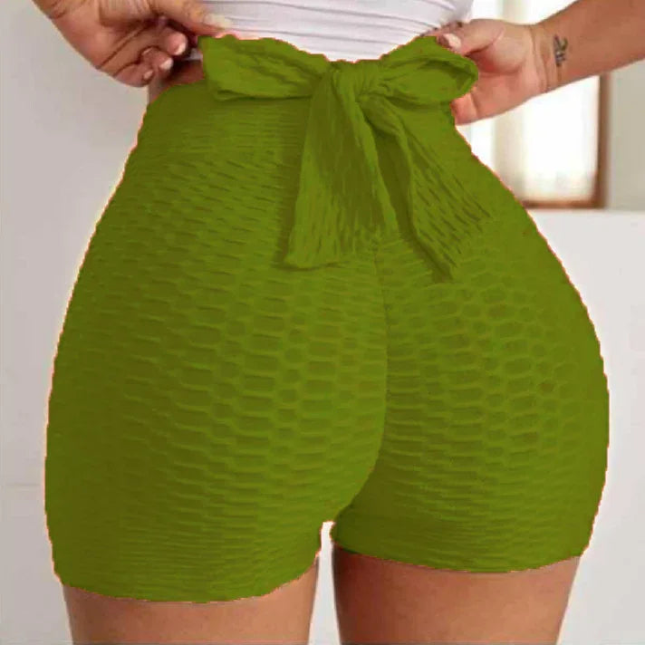 Green textured high-waisted shorts with bow, close-up fashion detail