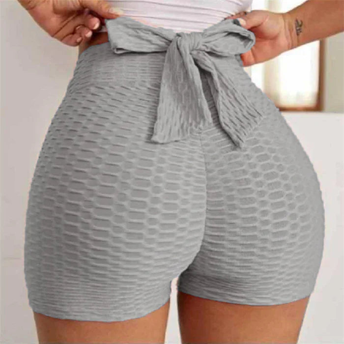 High-waisted textured gray workout shorts with waistband bow, close-up view