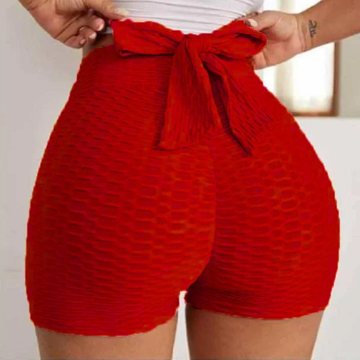 Red textured high-waisted shorts with a bow tie on a woman in a bright room