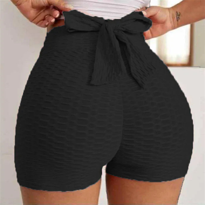 High-waisted black textured workout shorts with a bow tie waistband, close-up view