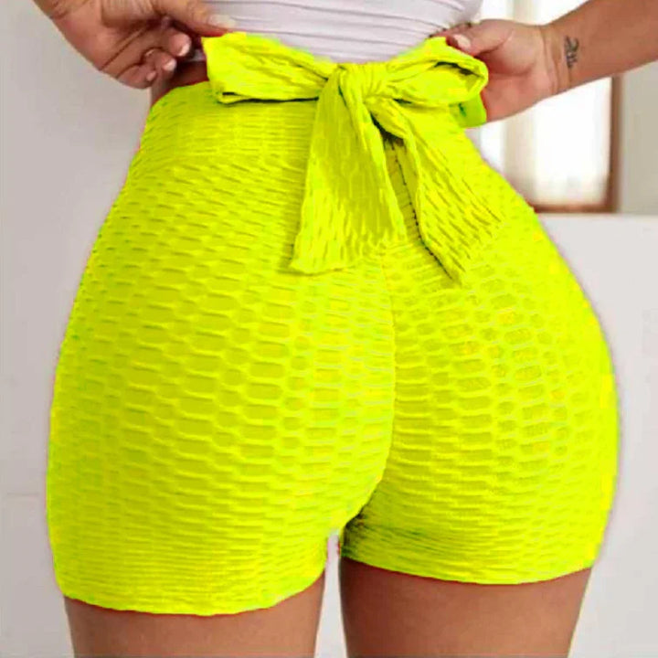 Woman wearing textured neon yellow high-waisted shorts with a bow tie at back