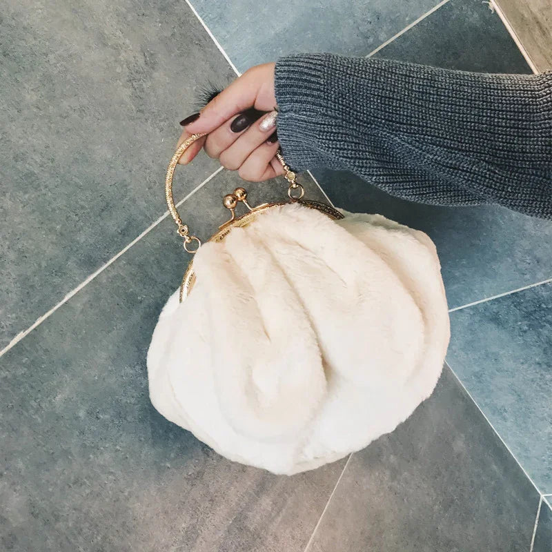 Hand holding a white faux fur handbag with gold clasp and handle on gray tiled floor