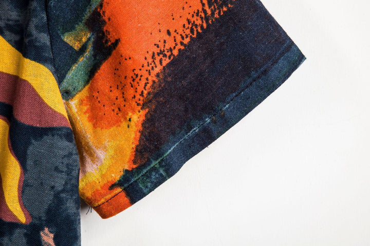 Close-up of colorful short sleeve fabric with abstract design in orange, yellow, black, and blue