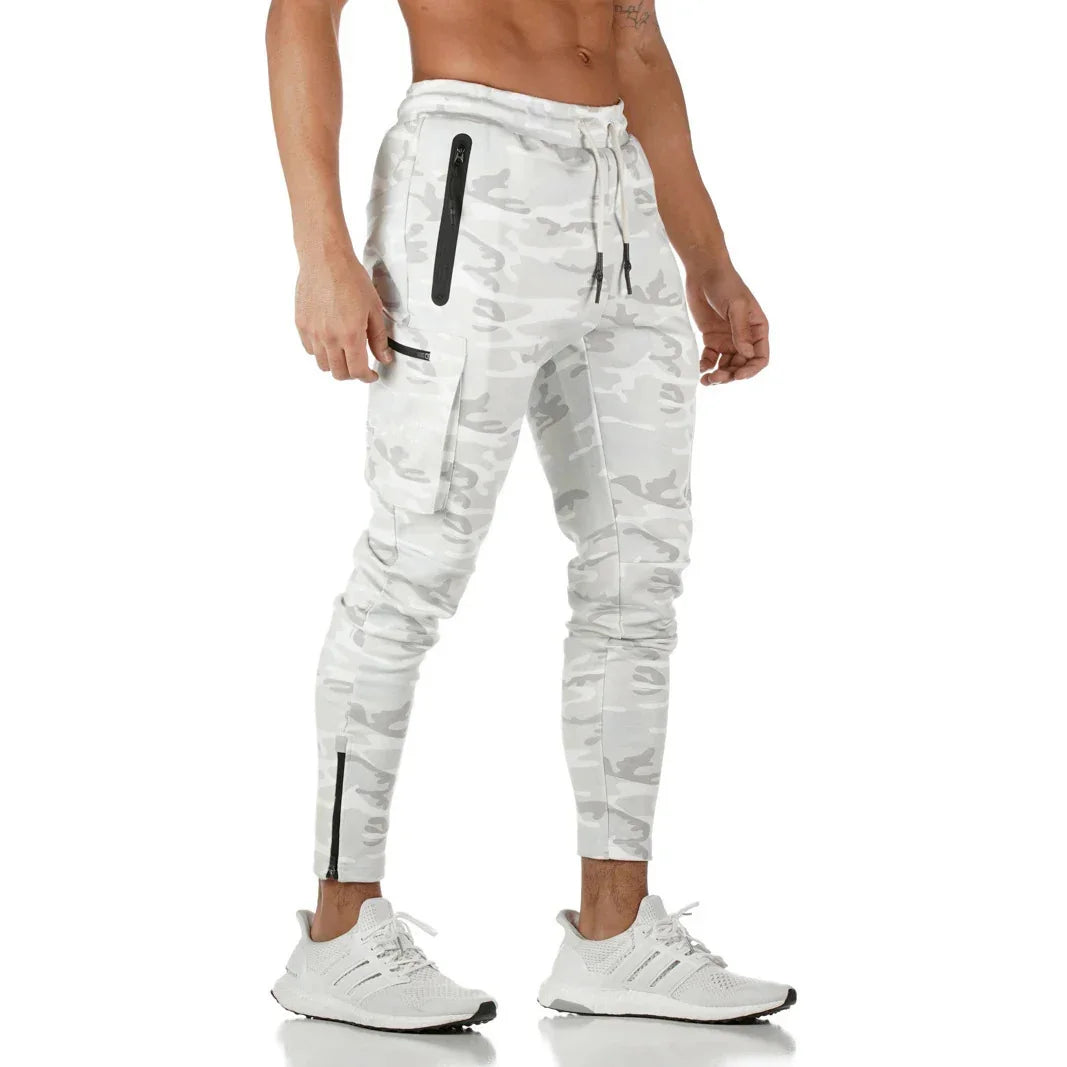 Men's white camo jogger pants with zippered pockets and drawstring waist paired with white sneakers