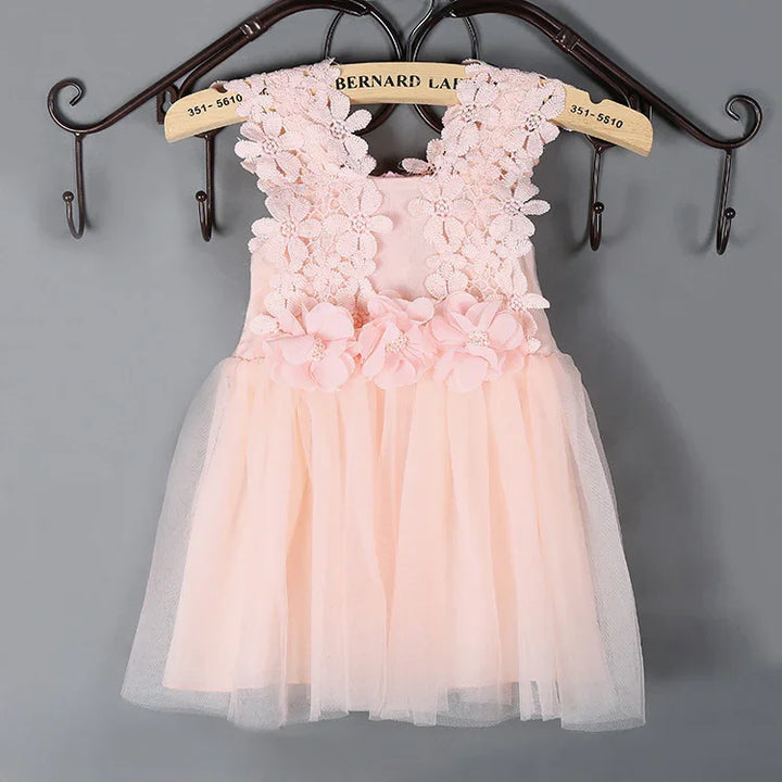 Pink sleeveless baby dress with floral lace bodice and tulle skirt, hanging on wooden hanger