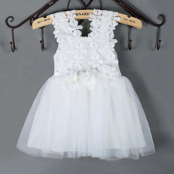 White sleeveless baby dress with floral lace bodice and tulle skirt hanging on wooden hanger