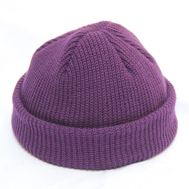Close-up of a purple knit beanie with a folded brim on a white background