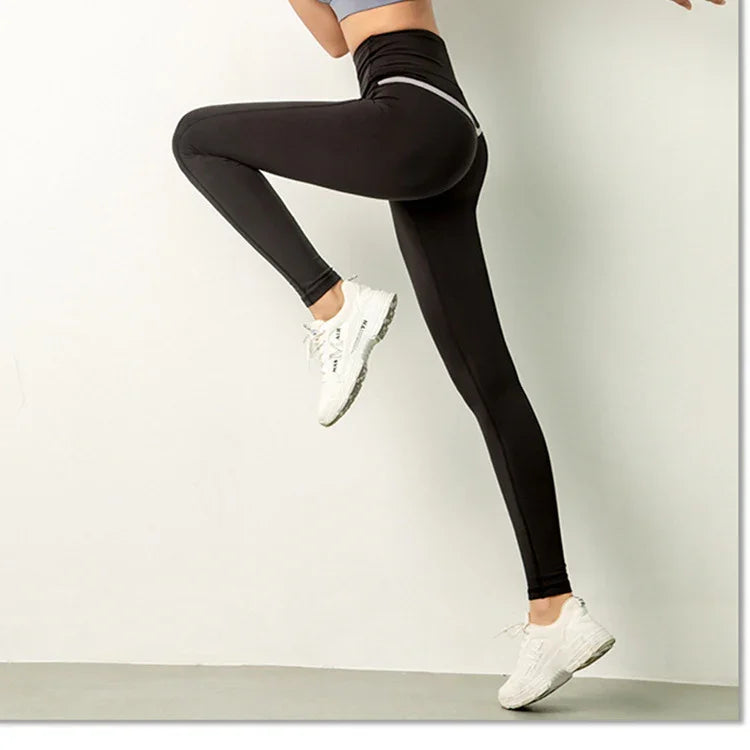 Woman wearing black high-waisted leggings and white sneakers in active pose