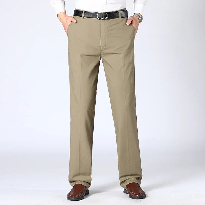 Men's beige casual pants paired with brown shoes and black belt, front view on plain background
