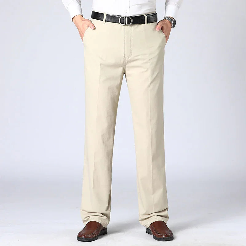 Men's beige formal trousers paired with brown loafers, white shirt, black belt, and wristwatch