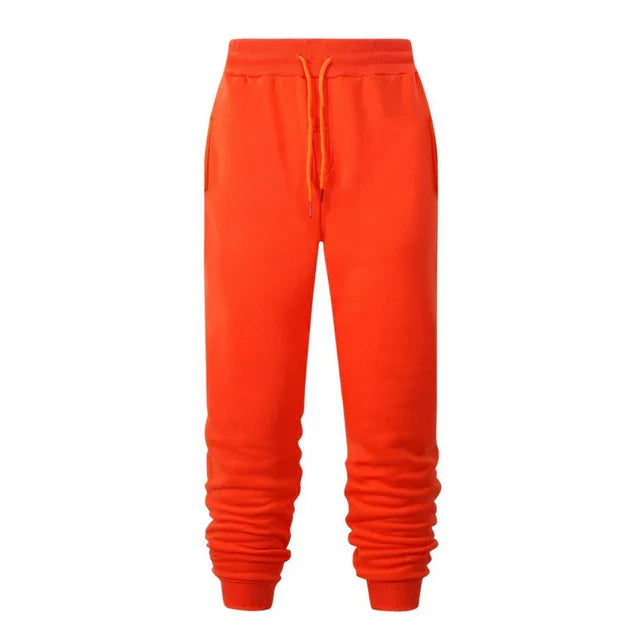Bright orange jogger sweatpants with elastic cuffs and drawstring waist on white background