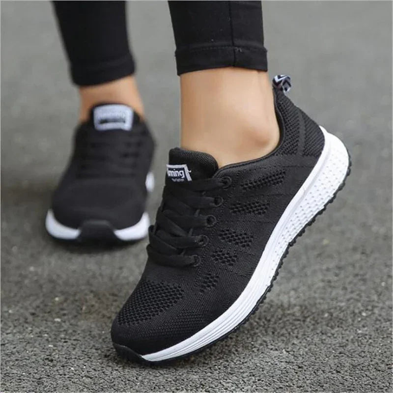 Black breathable running shoes with white soles on a person standing on asphalt