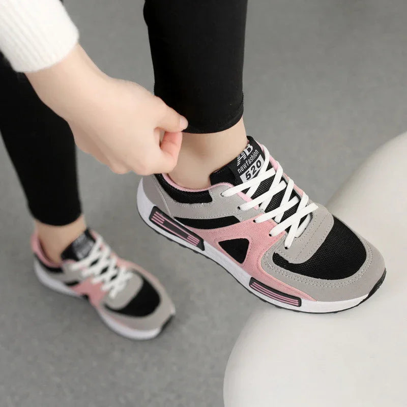 Person wearing black leggings adjusting pink black and gray New Fashion 520 sneakers indoors