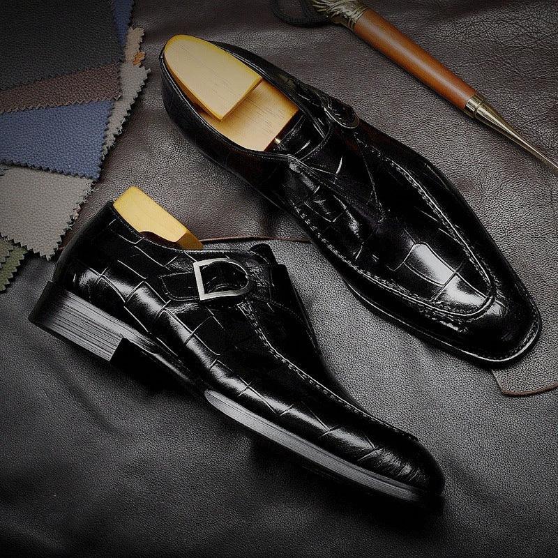 Black crocodile leather dress shoes with silver buckle and wooden shoe trees on leather surface