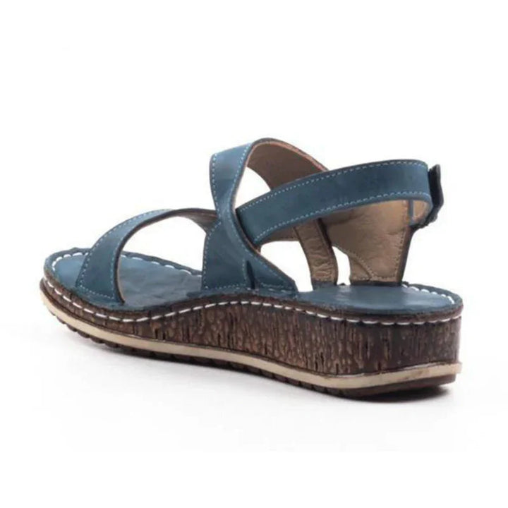 Blue leather wedge sandal with cross straps, cushioned insole, and textured brown sole