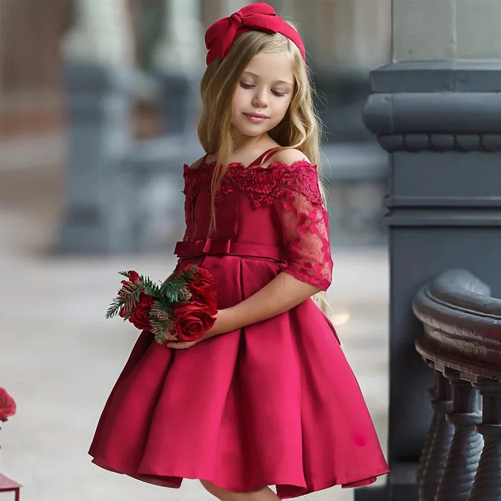 Young girl in elegant red off-shoulder dress with lace sleeves holding red roses bouquet