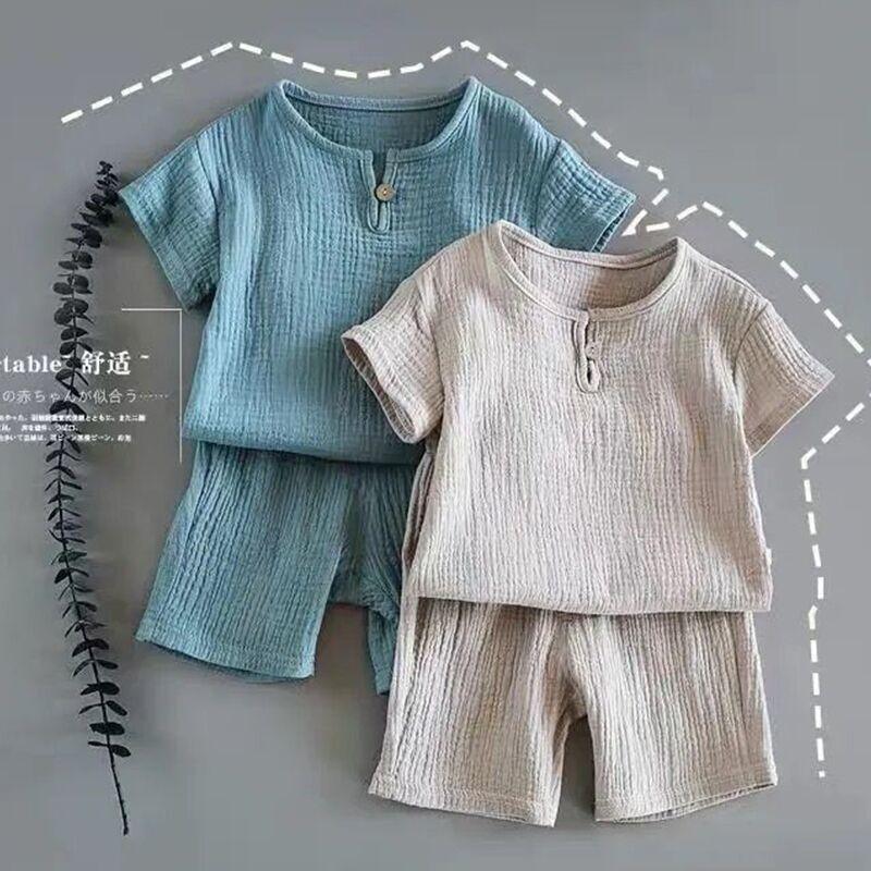 Two soft textured short sleeve toddler outfits with shorts, one blue and one beige, on gray background