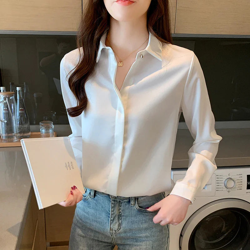 Woman in white blouse and blue jeans holding a book in modern kitchen with washing machine